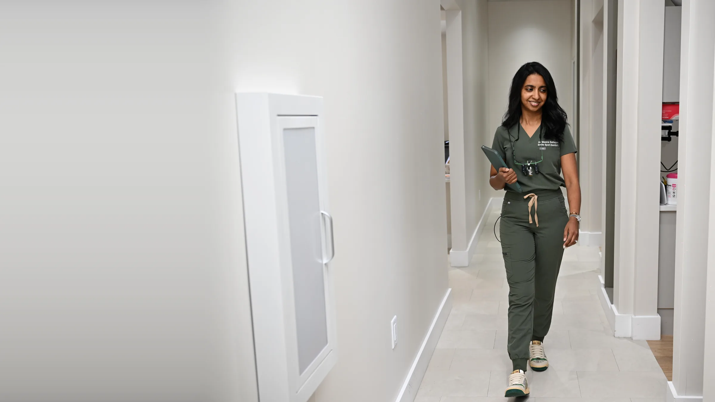 Dr. Meenachi Sellappan walking through the treatment corridor at Smile Spot Dentistry in Venice, FL